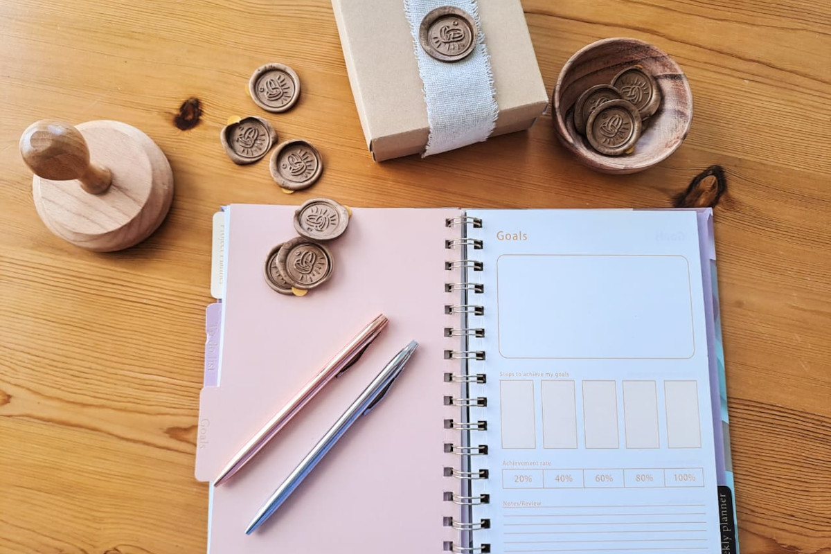 A notepad, pen, and wax seal elegantly arranged on a wooden table, symbolizing wedding planning in Mykonos.