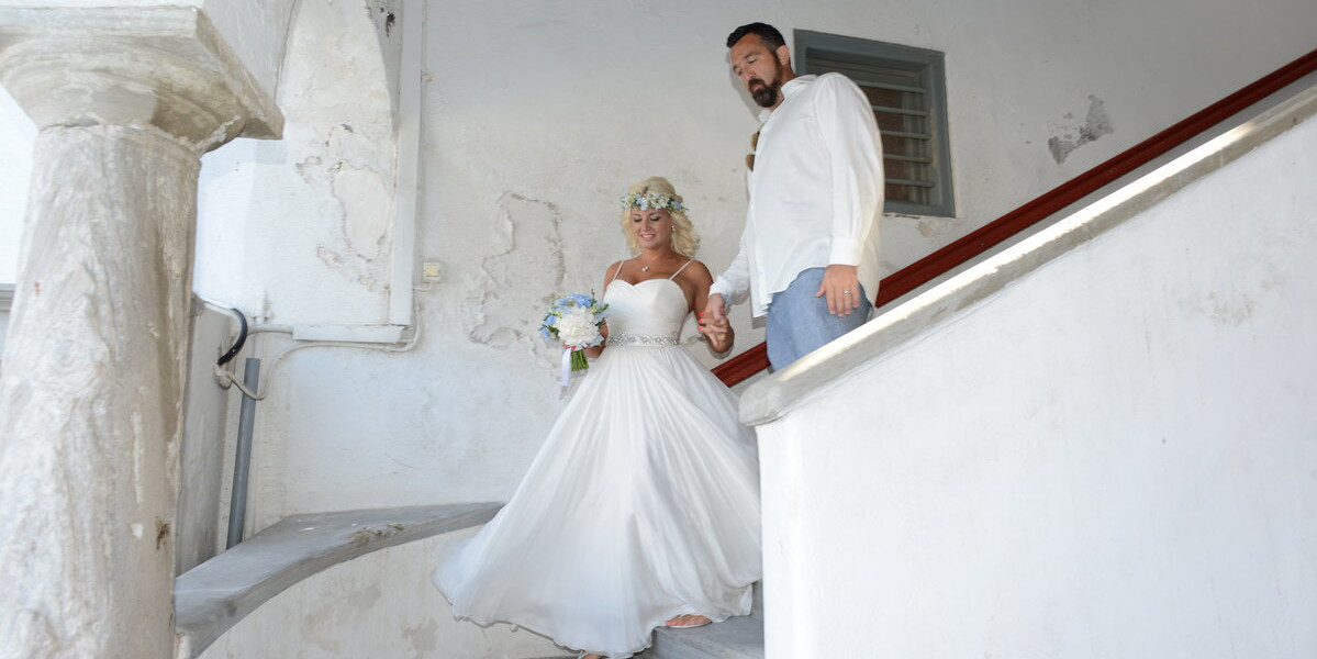couple walking down the traditional stairs of mykonos town hall , mykonos wedding packages