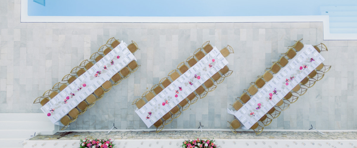  An elegant wedding table set up by a pool at a luxury villa in Mykonos, adorned with floral arrangements and fine dining settings.